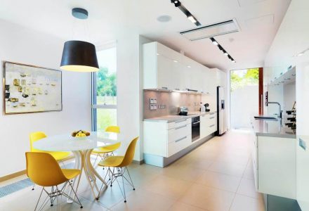 House kitchen in nice colors mostly white and yellow, with a small table and four chairs.